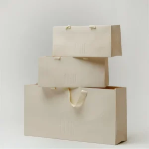 Custom Blind Deboss Logo Cream Beige Long Paper Gift Bag Wide Satin Ribbon Handle Luxury Clothing Boutique Packaging Tote Bag