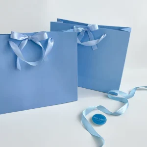 Custom Durable Baby Blue Paperboard Gift Bag with Satin Bow Ribbon Handle Matte Laminated Luxury Craft Packaging for Cosmetics